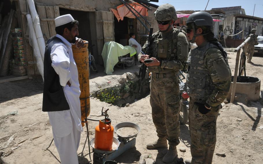Spc. Darren Boerl, center, talks with a merchant in the Baraki Rajan bazaar in Logar province, Afghanistan, with the help of an Afghan interpreter during a recent weekday patrol.
