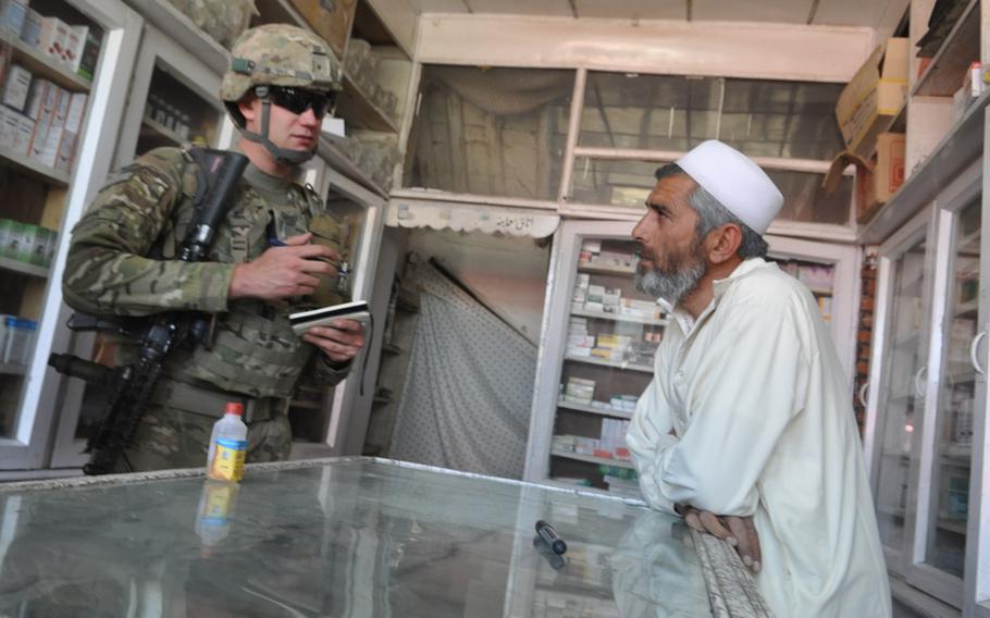 Spc. Darren Boerl chats with the owner of a pharmacy in the Baraki Rajan bazaar in Logar province, Afghanistan,  during a recent weekday patrol.