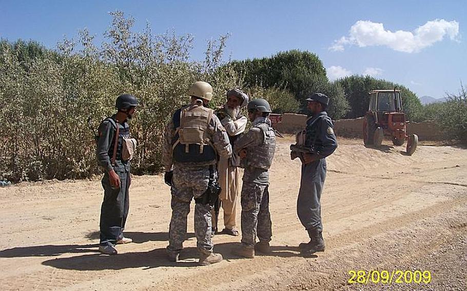 Days before he opened fire on American soldiers killing two and wounding three on Oct. 2, 2009, Said Kabeer, far right with rifle, an Afghan police officer known to the U.S. troops who trained and patrolled with him as Crazy Joe, talks with talks with U.S. and Afghan personnel.