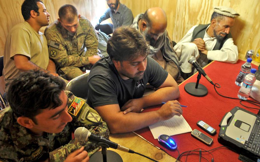 First Sergeant Ajmal Safi speaks to listeners on Shamla Voice, a call-in radio show produced on American Combat Outpost Nerkh in Wardak province. To the right sit Shamla host Gulab Kochai, local police commander Mohammad Gul Torkai, and Afghan National Police Colonel Mohammed Faroq Sidiqi (wearing cap) listen in.