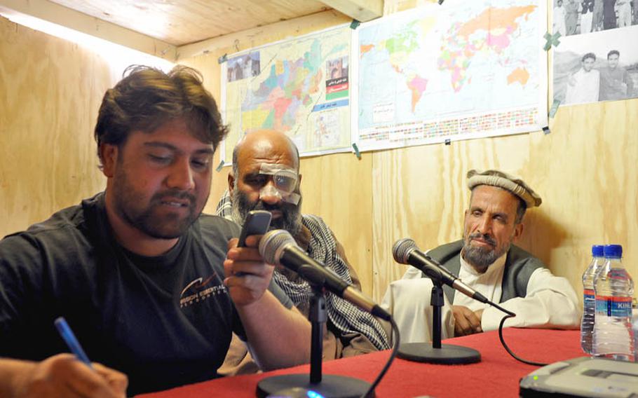 Shamla Voice host Gulab Kochai takes a call Friday inside the broadcast booth on COP Nerkh. Beside him, local police commander Mohammad Gul Torkai and Afghan National Police Colonel Mohammed Faroq Sidiqi (wearing cap) listen in.