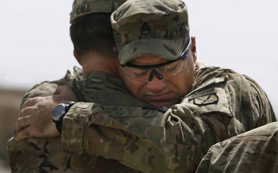 Staff Sgt. Michael Linnemeier hugs his company commander, Capt. Dennis Call, during a Saturday memorial service at Forward Operating Base Howz-e-Madad in Afghanistan. The memorial service was held in honor of five soldiers killed in an improvised explosive device attack on August 11 near Combat Outpost Nalgham.