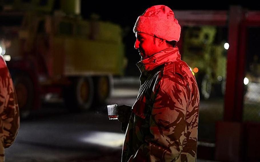 A Kuwaiti policeman drinks coffee to warm up as the first group of U.S. soldiers in the last convoy to leave Iraq drive across the Kuwait border at the Khabari crossing.

