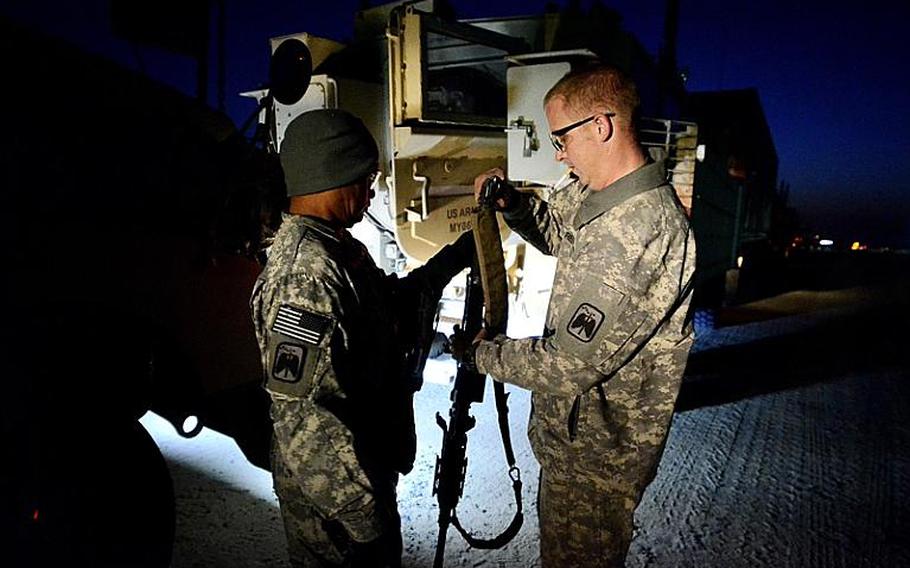 U.S. soldiers in the last convoy to leave Iraq help each other clear their weapons after safely crossing the Kuwait border at the Khabari crossing.