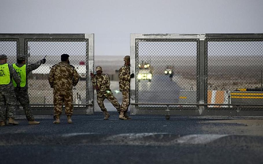 Kuwaiti policeman open the gate at the Khabari crossing ahead of a group of the last U.S. military convoy to exit Iraq.