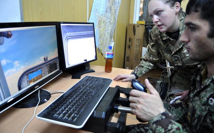 British Royal Air Force Flight Lt. Lilie Weaver guides Afghan Air Force 2nd Lt. Aziz Mohammadi through a flight simulation exercise at Thunder Lab, a joint American-British effort to build the English skills and aviation knowledge of prospective Afghan pilots.