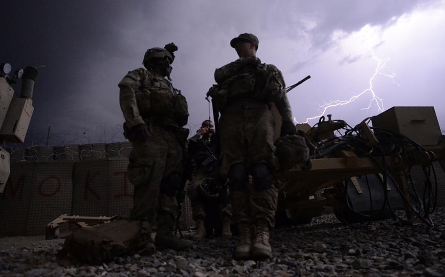 Spc. Devon Jackson, left, Pfc. Dillon Nguyen, middle, and Sgt. Nicholas Streeter, with Company A of the 1st Battalion, 501st Infantry Regiment wait for new orders in a thunderstorm after returning from the scene of a firefight between insurgents and U.S. forces in eastern Khost province. Two U.S. soldiers suffered minor injuries in the attack.