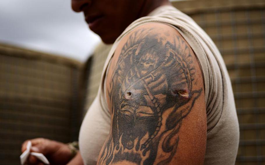 Staff Sgt. Damian Remijio shows the entry and exit wounds he sustained during a firefight with insurgents April 12, 2012. He was saved from further injury by the chest plate of his body armor, which stopped two bullets from an AK-47.