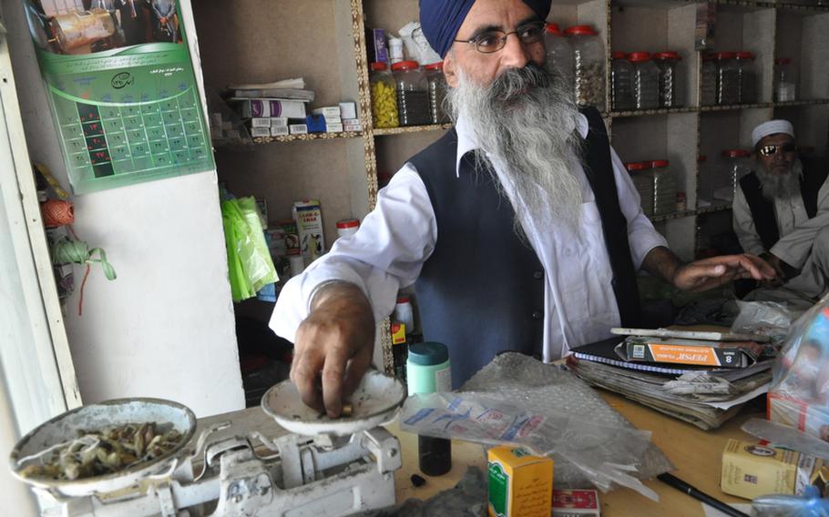 Tarlock Singh Jawaherzada weighs herbs at his traditional medicine shop in Kabul. Like many of Sikhs in Afghanistan, Jawaherzada wants to leave the country, saying he is tired of constant discrimination, violence and lack of opportunities.