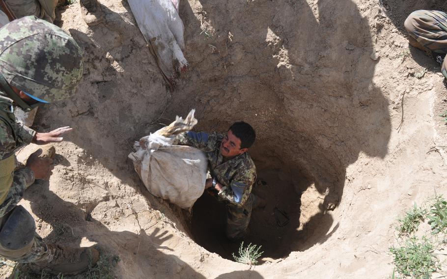 An Afghan soldier removes a bag of bomb-making materials stashed by insurgents in a farm field near the village of Muqur in Ghazni province. Col. Mohammad Wasil, the former commander of the battalion to which the soldier belongs, is suspected of selling weapons to militants.