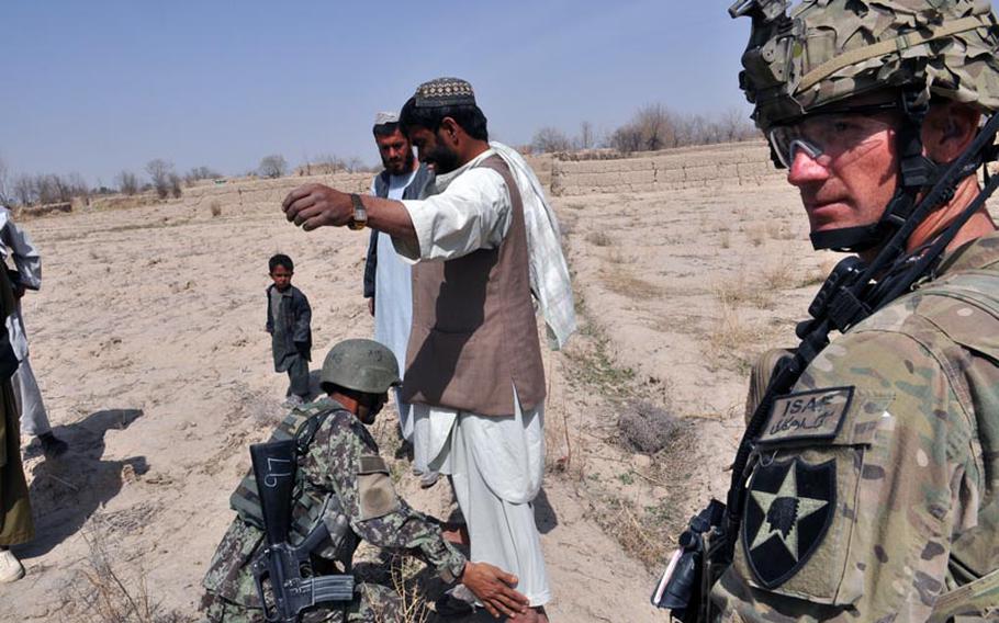 An Afghan soldier searches a villager in in Kandahar province while a U.S. soldier looks on. A spike in killings of international troops by their Afghan counterparts has coincided with an effort by the Western military coalition to hand off more security responsibility to Afghan forces.