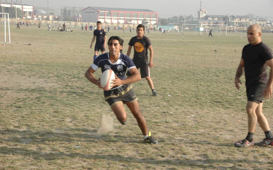 Khanjer Baig, a member of Afghanistan&#39;s national rugby team, runs with the ball during practice at Kabul&#39;s Chaman-i-Huzuri park on Sunday.