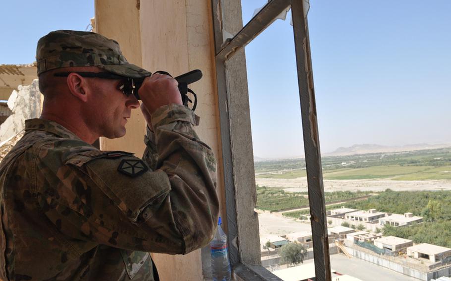 Command Sgt. Maj. Bill Johnson peers out a window of the "Guardian Angel" tower during a tour of Bagh-e-Pul, a police mentoring base on the outskirts of Kandahar in southern Afghanistan. 