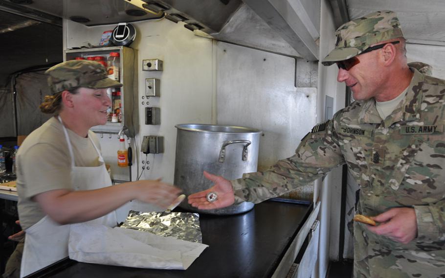 Command Sgt. Maj. Bill Johnson gives a coin to a cook at Bagh-e-Pul, a police mentoring base on the outskirts of Kandahar in southern Afghanistan.