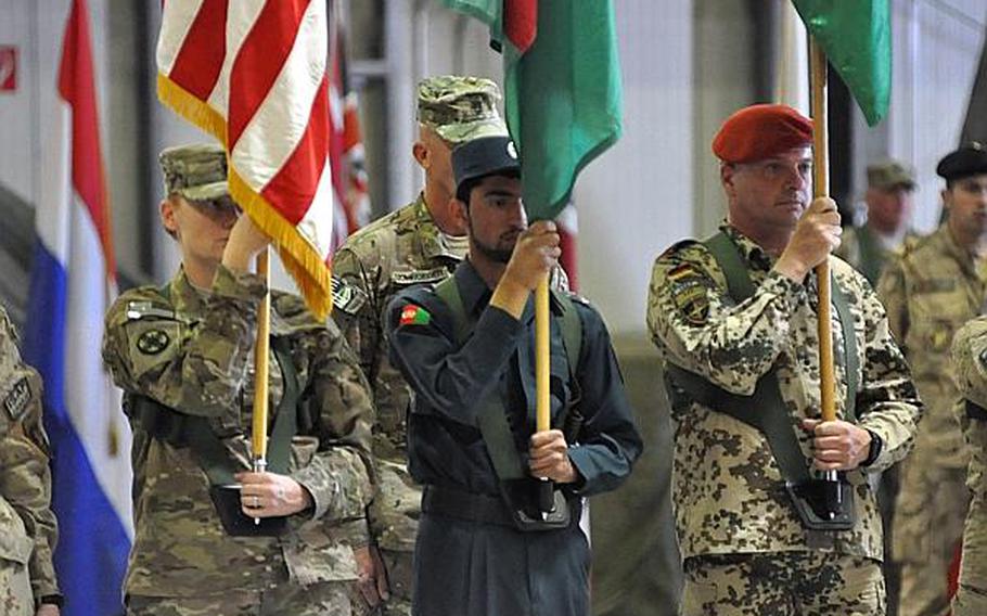 An Afghan National Police officer holds the Afghan flag next to two International Security Assistance Force soldiers at a change of command ceremony at Kabul International Airport. Lt. Gen. James L. Terry relinquished his position as head of ISAF Joint Command to Lt. Gen. Mark A. Milley.
