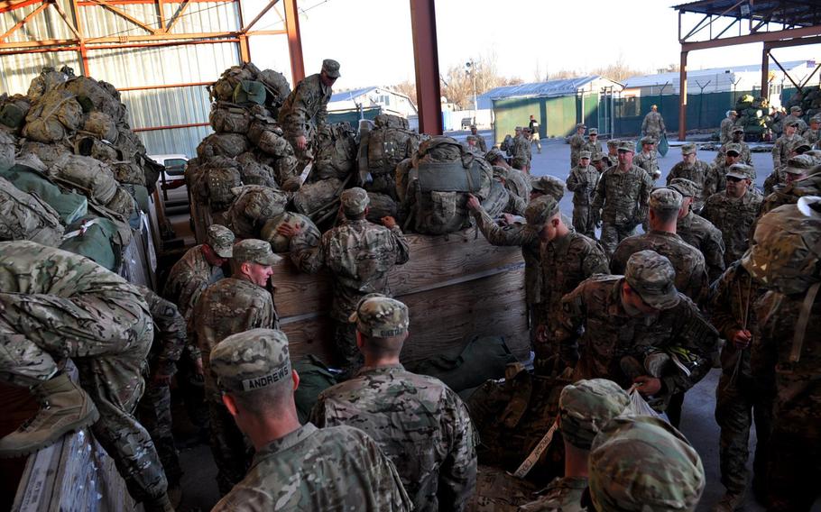 Soldiers from the 1st Battalion, 506th Infantry Regiment, 101st Airborne Division, dig through wooden bins full of duffel bags and backpacks as they prepare for customs inspections at Manas Transit Center in Kyrgyzstan.