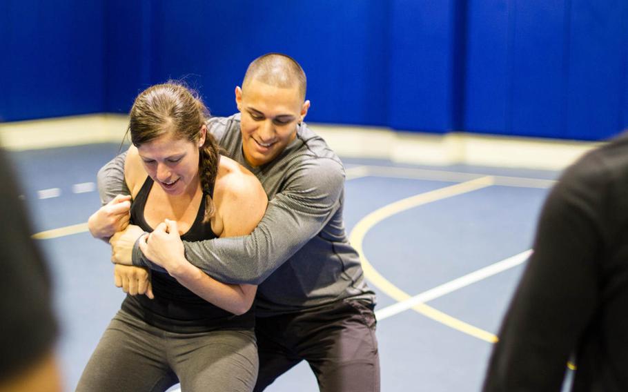 Petty Officer 1st Class Kalindi West attempts to break away from Sgt. William Rivera using a self-defense technique she just learned at a new self-defense class at Naval Support Activity Bahrain, Dec 5, 2014.