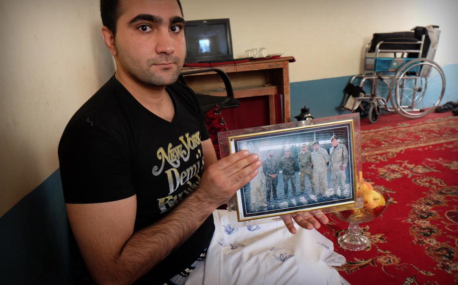 Qandagha Qandaghari, a former commander of an elite police unit, displays a photo of international military advisers with whom he worked before losing both his legs to a roadside bomb in Helmand in the summer of 2014. He says he feels frustrated that he hasn't been able to apply his education and training to another job in the security forces.