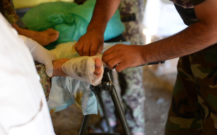 An Afghan army medic bandages the foot of a soldier injured during an operation in Nangarhar province last month. Wounded soldiers and police were treated at this forward aid station, but then often had to wait hours or even a day to be evacuated to a better hospital.