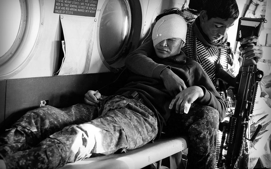 Inside an Afghan Air Force Mi-17 helicopter, a soldier comforts a comrade injured by an improvised bomb in Uruzgan province on Jan. 6, 2014. Afghan security forces have taken the brunt of casualties in the unfinished war as international troops have withdrawn.