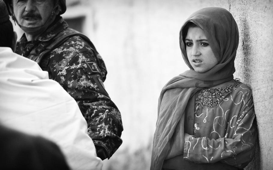 A girl watches Afghan security forces pass through her village during a patrol in southern Afghanistan. Despite the proclaimed end of combat by international forces, continuing violence has left record numbers of Afghan civilians killed or wounded, according to United Nations officials.