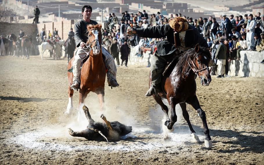A buzkashi player scores by dropping a calf carcass in a chalk circle during a match on the outskirts of Kabul on Jan. 15, 2015. Individual riders can win money and other accolades by wrestling the calf from dozens of other competitors, carrying the carcass around a flag, and dropping it in the "end zone."
