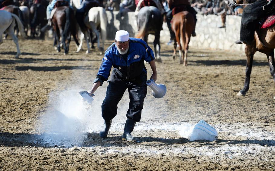 An official uses chalk to mark the goal used during a buzkashi match in Kabul on Thursday, Jan. 15, 2015. The circle of chalk is often trampled beyond recognition by the hooves of dozens of horses, requiring near constant attention by the official.