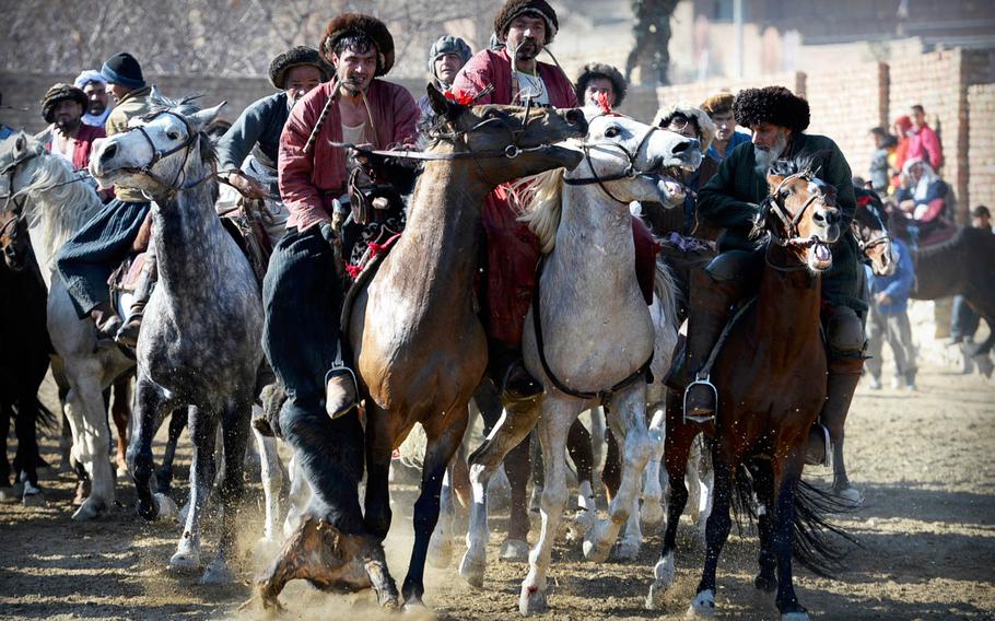 One rider, left, tries to keep a calf carcass from his competitors during a buzkashi match on the outskirts of Kabul. The game involves almost constant contact between horses and their riders.