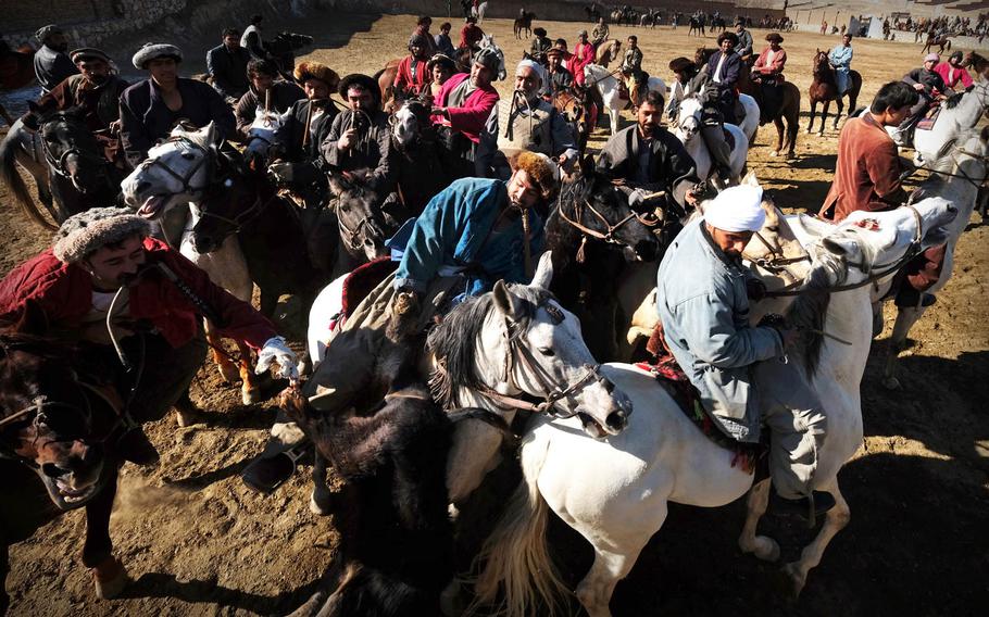 Buzkashi riders wrestle over a calf carcass during a game outside Afghanistan's capital on Thursday, Jan. 15, 2015. The players hold whips in their teeth to free their hands to grab the calf.