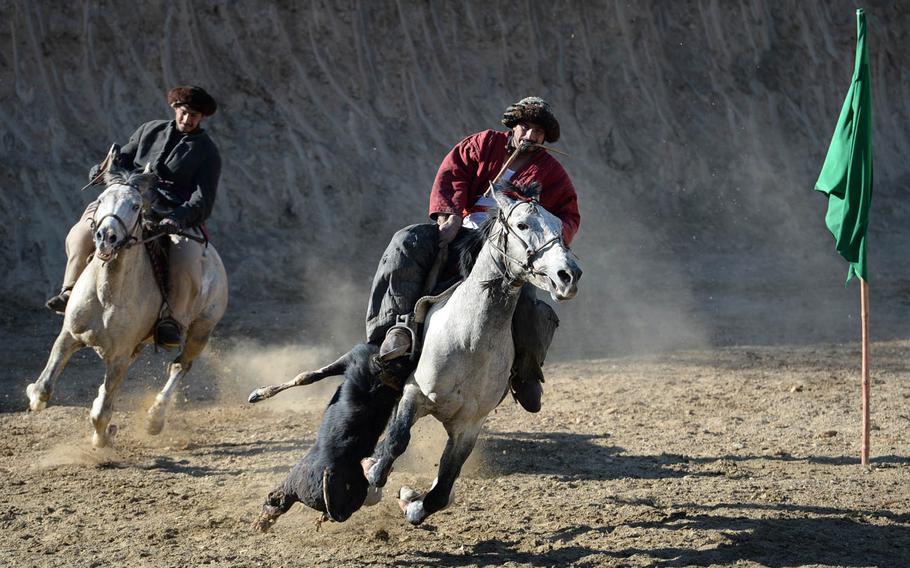An Afghan buzkashi player rounds the green flag before attempting to drop a calf carcass in a chalk circle at the other corner of the field during a game outside Kabul on Thursday, Jan. 15, 2015. Other players try to steal the calf and score for themselves.