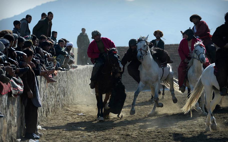 Buzkashi players ride past the crowd at a match on the outskirts of Kabul on Jan. 15, 2015. Spectators often have to run or leap out of the way when the pack of horses abruptly switches direction and charges into the crowd.