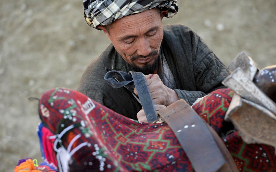A man adjusts a saddle on his horse during a buzkashi game outside Kabul on Jan. 15, 2015. Matches rarely last for a predetermined amount of time and individual riders often have to stop to rest their horses before continuing.