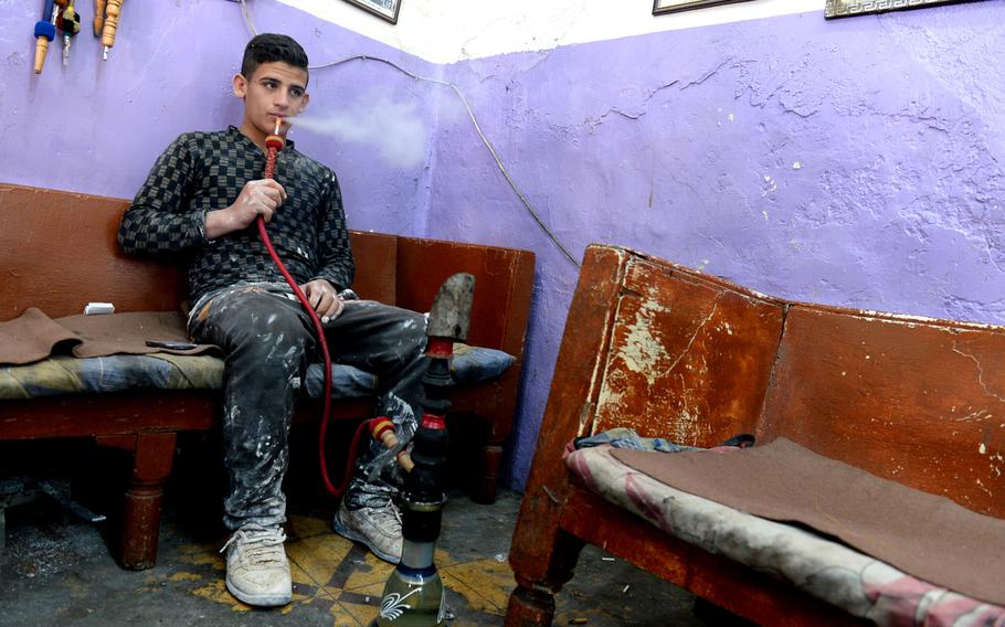 Haider al-Nada, 21, smokes a waterpipe at a cafe in old town Baghdad in late April 2015. A house painter, he says work has slowed in recent months as the local economy has stagnated.