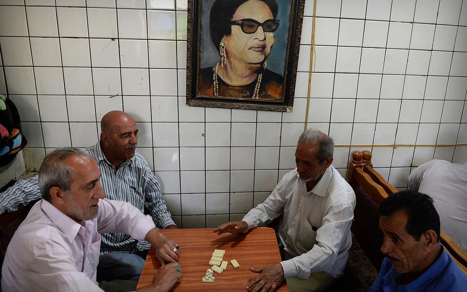Men play dominoes under a painting of Egyptian singer Umm Kulthum in a cafe in Baghdad. While some residents say the restaurant crowd has thinned in the face of regular suicide attacks, many sidewalk cafes in older parts of the city remain packed.