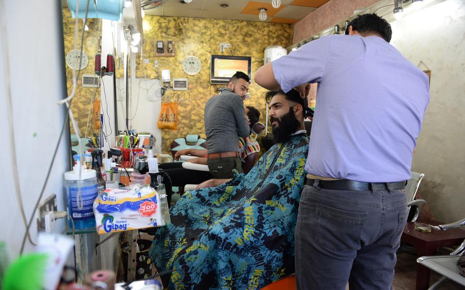 Men get their hair cut at a barbershop in Baghdad. Areas of street-side shops and stores remain crowded and busy despite the city's dangerous reputation.