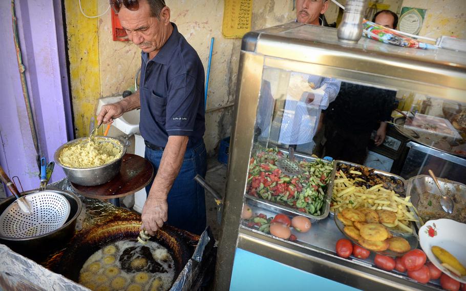 A street vendor in Baghdad fries falafel, usually made from ground chickpeas or fava beans, often served in a flat bread sandwich.  Other common fast food includes shawarma, and boiled chickpeas.