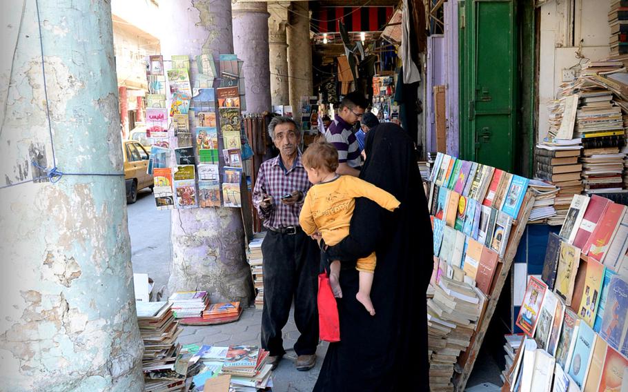 A woman carries her child past shops in Baghdad's old book market. In 2007, a suicide bomber killed 26 people in the area, which wasn't officially reopened for a year.