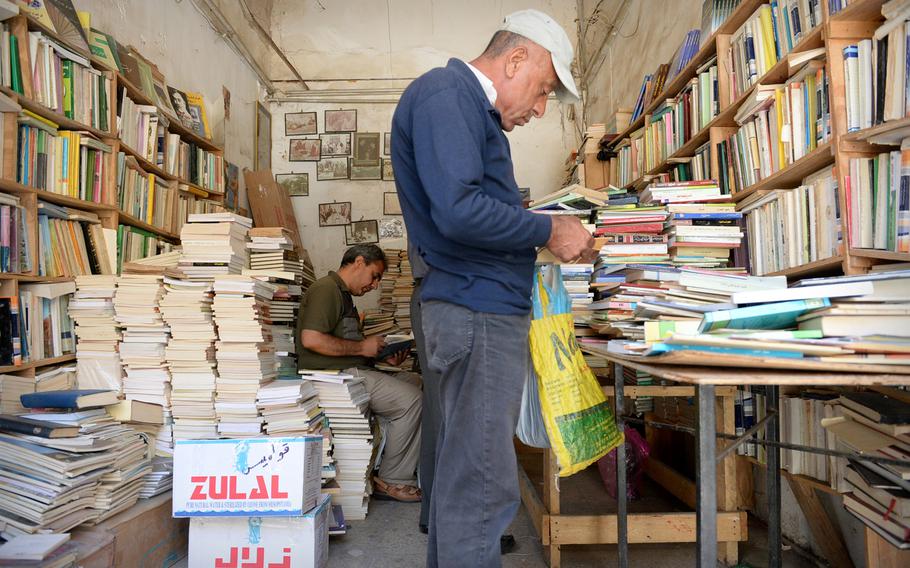 Two men browse books at a shop on Mutanabbi Street. The area hosts a range of bookshops and cafes and is often seen as a favorite haunt for the city's intellectuals.