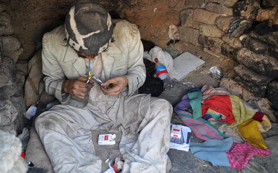A man smokes heroin in Dahne Kamarkalagh, a colony of drug addicts on the outskirts of Herat, Afghanistan, in October 2013.  More than one in 10 Afghans regularly uses illegal drugs according to a survey released Tuesday, May 12, 2015.