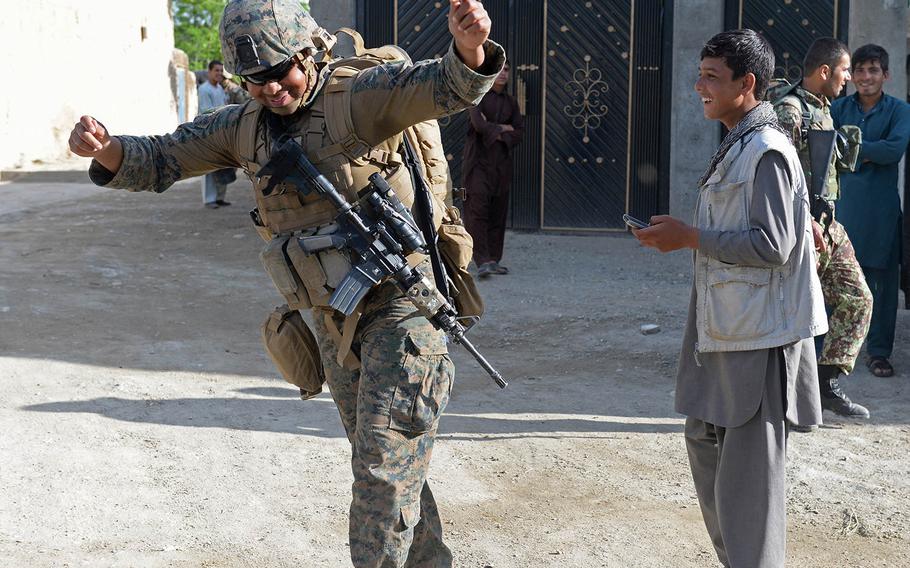 Petty Officer 2nd Class Christopher Johnson, a corpsman, dances to a villager's cell phone music while on patrol near Bagram Airfield May 9, 2015. About 50 Marines work with Georgian Army partners to secure Bagram Airfield.