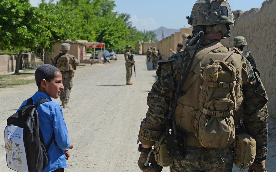 Marine Capt. Doug Capra, a joint terminal attack coordinator, is accompanied on patrol by an Afghan child near Bagram Airfield May 9, 2015. Capra is among  about 50  Bagram-based Marines who make up the only Marine unit in Afghanistan.