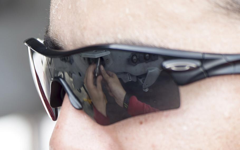 An aviation ordnanceman prepares a jet prior to attaching a munition to it onboard the aircraft carrier USS Theodore Roosevelt Aug. 14, 2015.  His hands are reflected in his glasses.