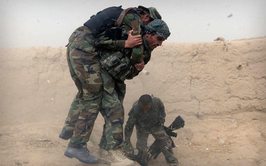 Dust and debris shower an Afghan soldier as he carries a comrade injured during a firefight with Taliban gunmen on the outskirts of Kunduz city. The battle for Kunduz is only one of many that have played out across northern Afghanistan as the Taliban have launched offensives.