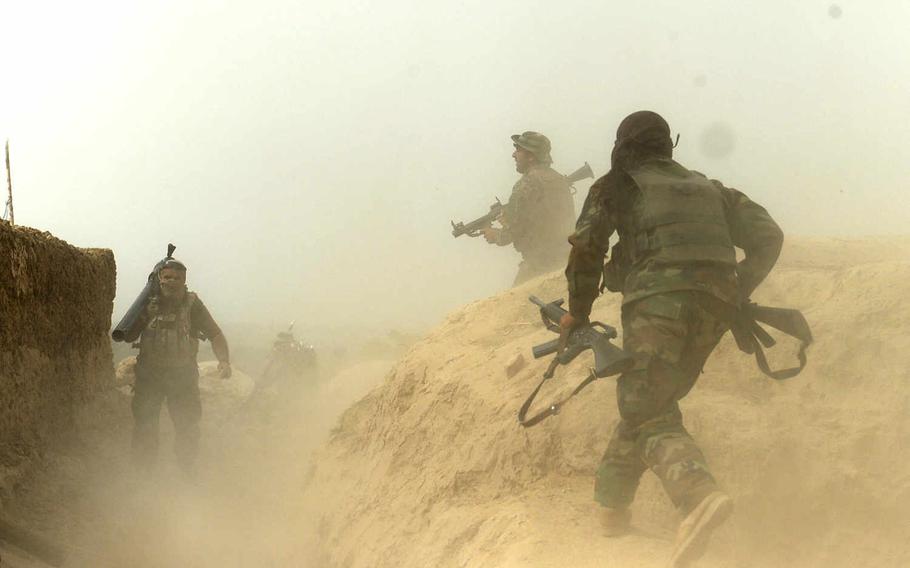 Afghan army soldiers run for position during a firefight with Taliban gunmen in Kunduz city. It took government troops about two weeks to dislodge most Taliban fighters.