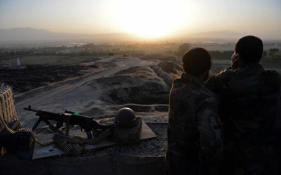Two Afghan soldiers at a base near the Kunduz airport watch the sun set over Taliban positions across the Kunduz river. Most government troops felll back to the airport and its nearby military bases when the Taliban overran the city.
