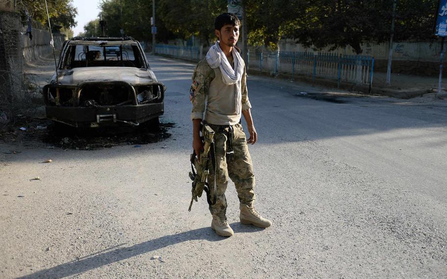 An Afghan police officer mans a checkpoint next to a burned-out military truck in Kunduz after security forces pushed Taliban fighters from the city's center. The capabilities of the NATO-trained forces have been called into question by the Taliban's brief occupation of the city.