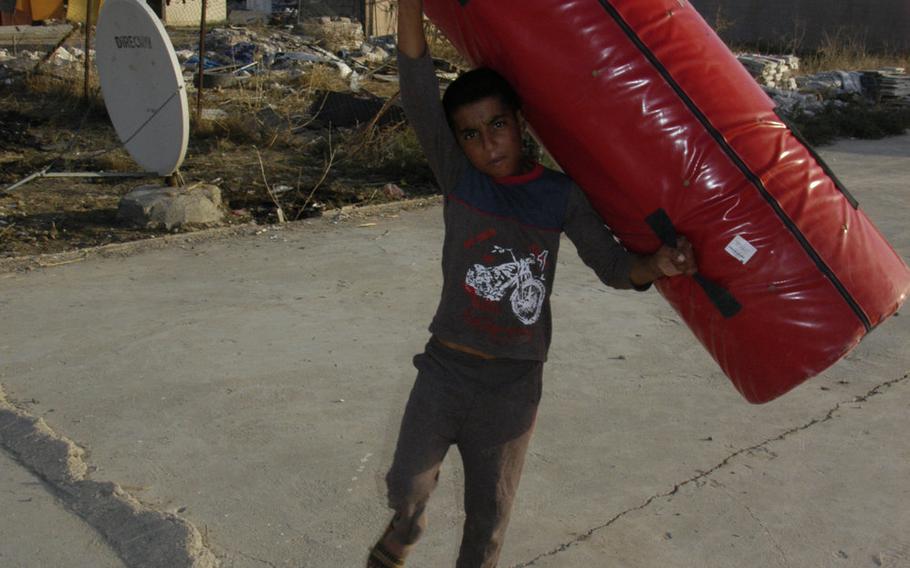 A Yazidi boy totes a rugby tackle bag in Irbil, Iraq, on Sunday, Oct. 25, 2015.