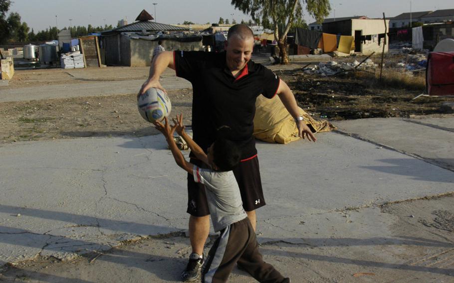 Logistics company worker Neil Young, of Scotland, plays rugby with a Yazidi boy at a camp for displaced people in Irbil, Iraq, on Sunday, Oct. 25, 2015.
