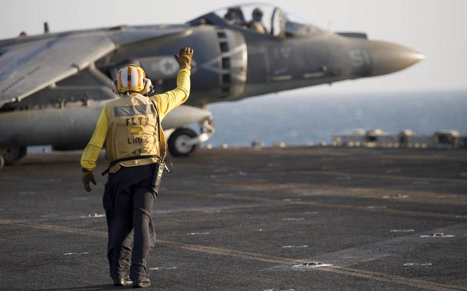 Petty Officer 1st Class Areseli Morales, a plane shooter, directs the Marine pilot of an AV-8B Harrier from the 15th Marine Expeditionary Unit preparing to launch from the flight deck of the USS Essex, Oct. 13, 2015.