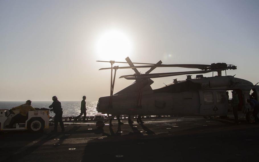 The flight deck crew of the multipurpose amphibious assault ship USS Essex prepares to tow an MH-60 Seahawk on Oct. 13, 2015.